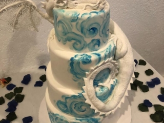 four tier blue and white watercolor painted fondant cake with resting dragon figure