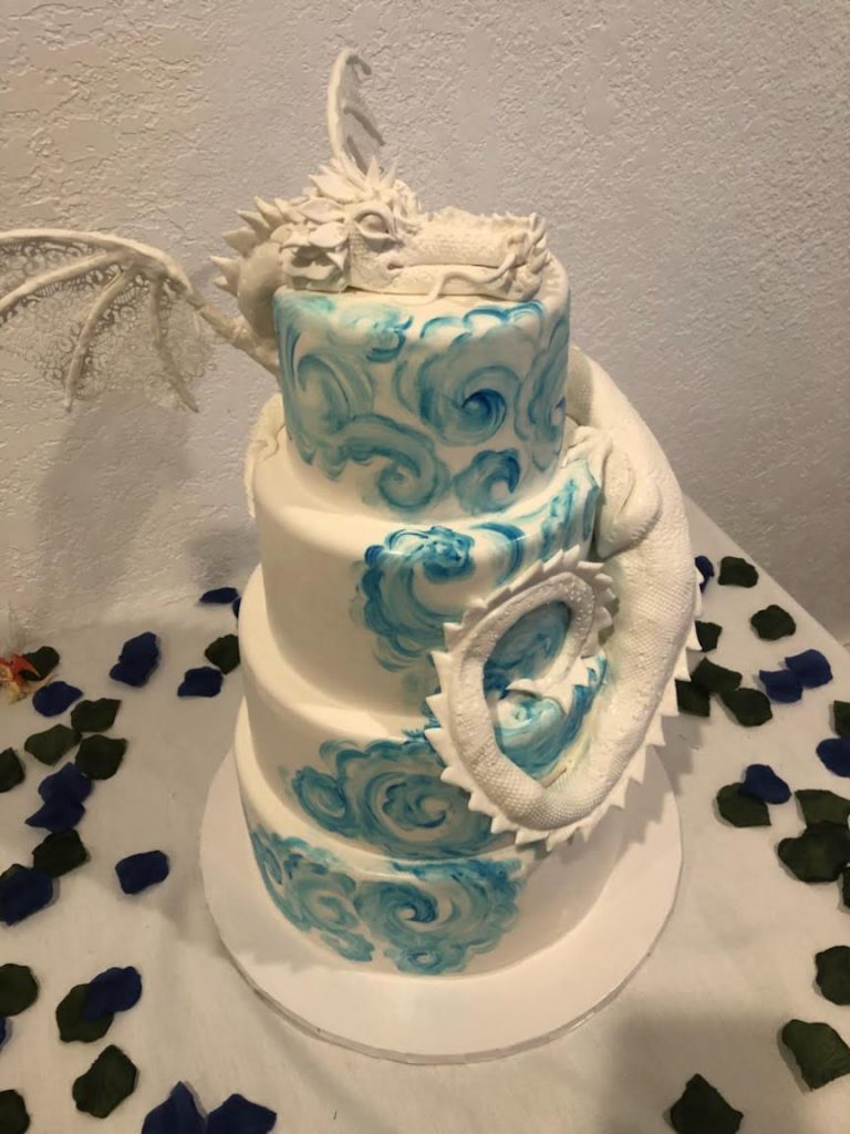 four tier blue and white watercolor painted fondant cake with resting dragon figure